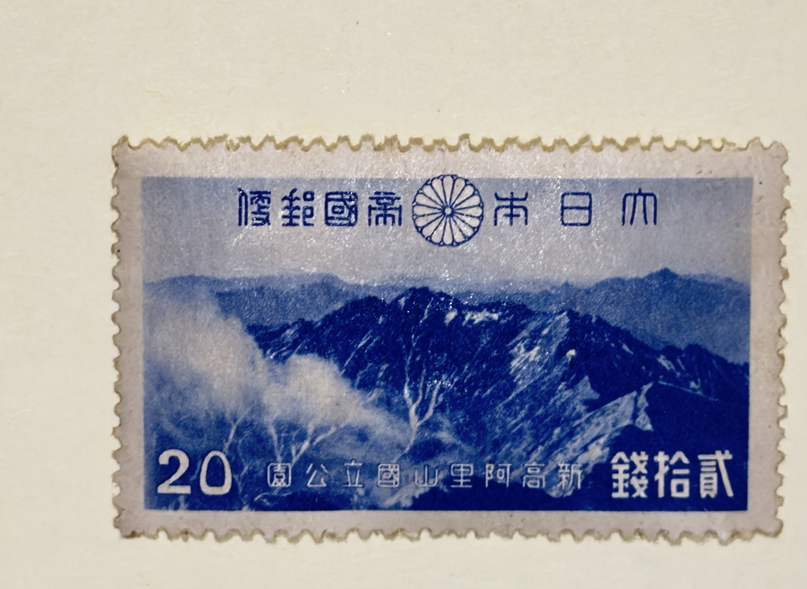 Blue 20-sen Niitaka-Arisan National Park stamp photographed on a pale album page
